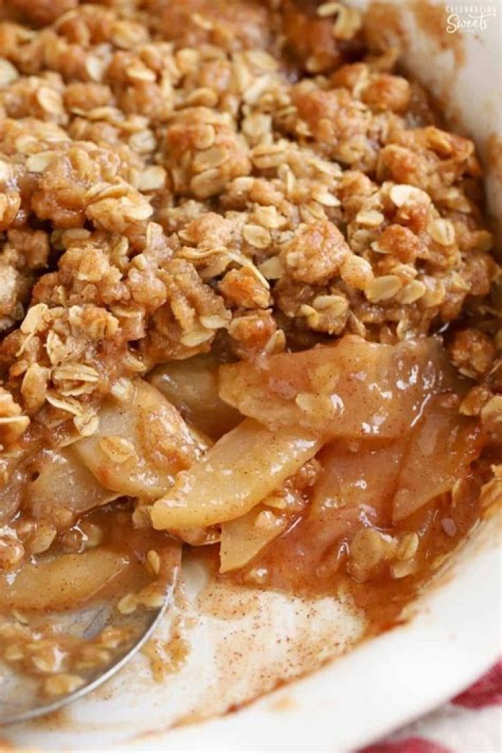Apple crisp in a white bowl topped with yogurt.