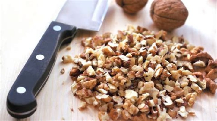 Chopped nuts and chocolate chips in a bowl of chocolate cookie dough.