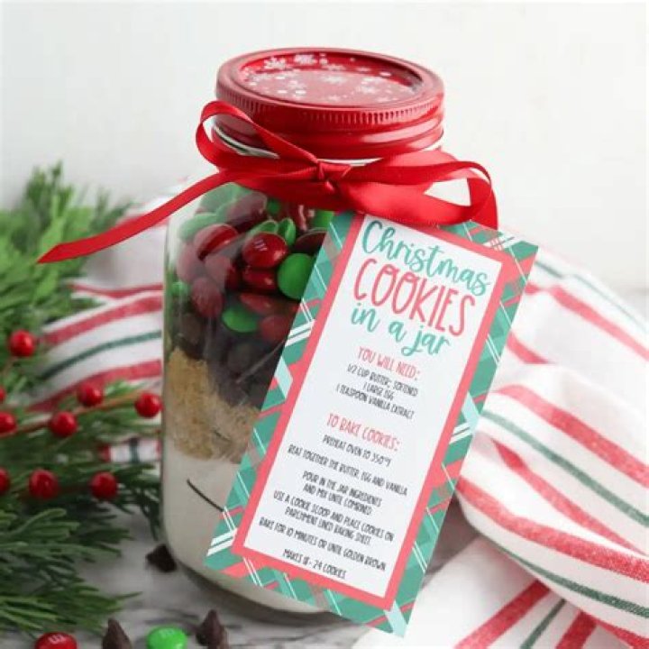 Christmas M&M cookie mix in a jar topped with red fabric and ribbon.