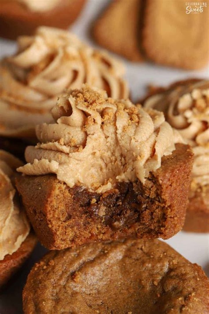 Gingerbread cookie cup topped with brown frosting on a white plate.
