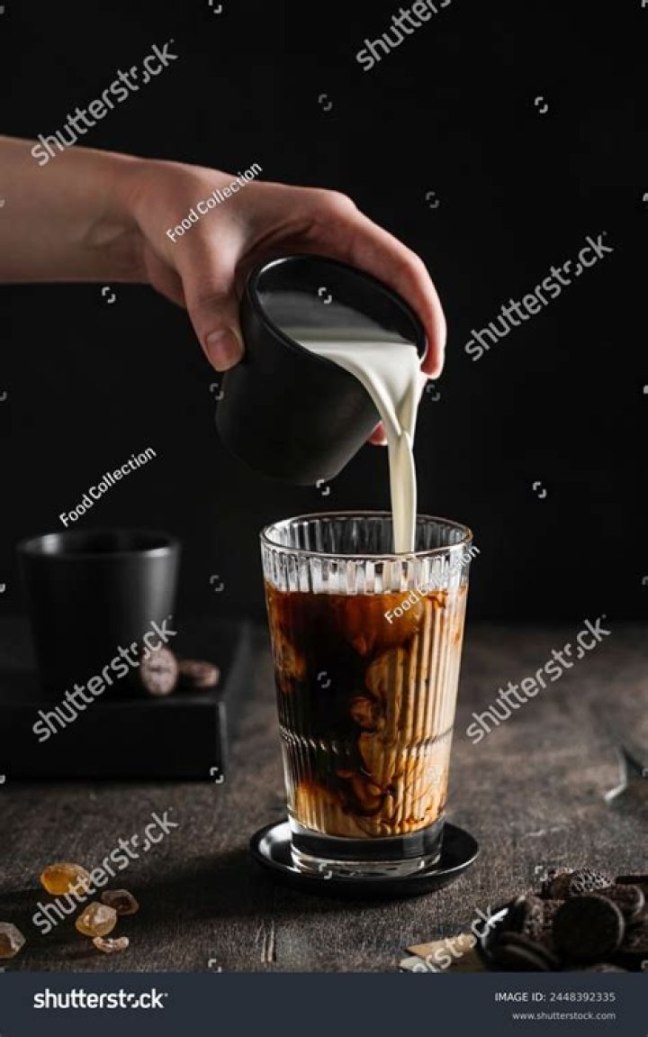 Milk being poured into iced coffee