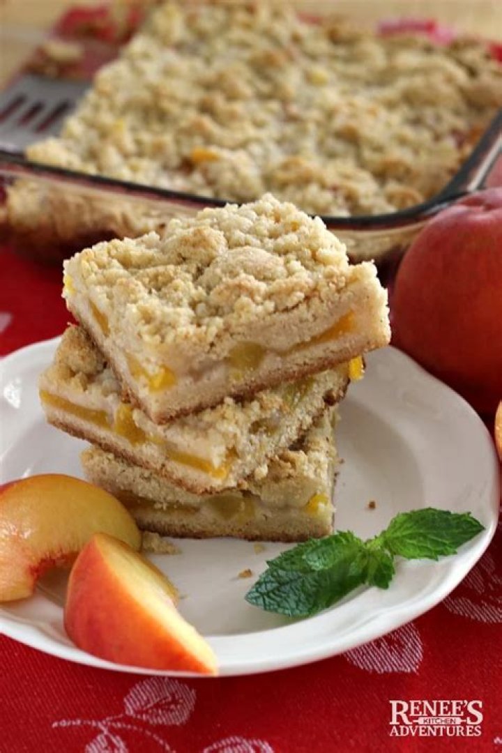 Peach crumb bars stacked on a wooden board