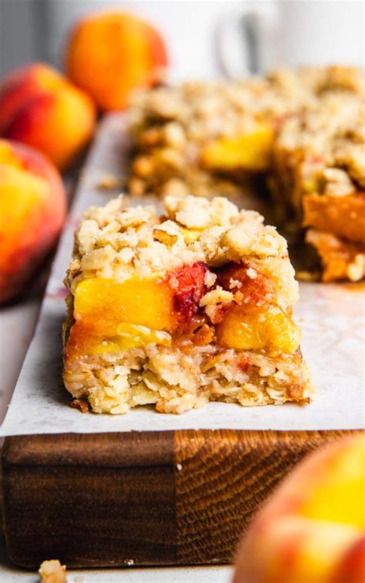 Two peach crumb bars topped with vanilla ice cream.