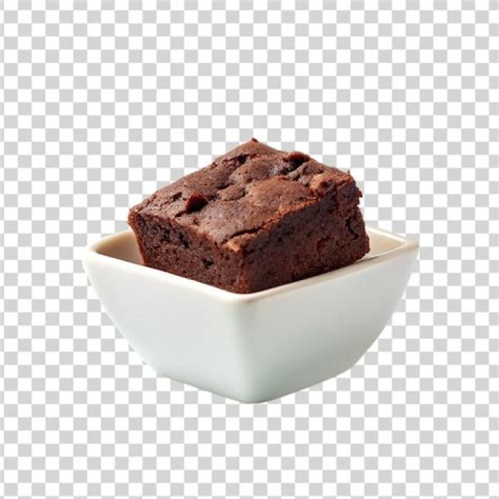 White bowl with a brownie inside, topped with vanilla ice cream and caramel sauce.